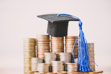Graduation hat on coins money on white background. Saving money for education or scholarship...