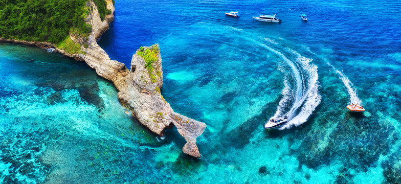 Fast boat at the sea in Bali, Indonesia. Aerial view of luxury floating boat on transparent turquoise water at sunny day. Panoramic seascape from air. Top view from drone. Travel - image