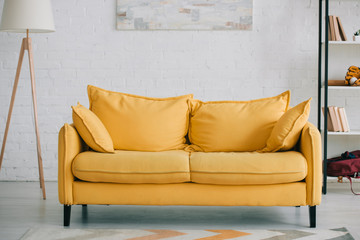 spacious, light living room with bright yellow sofa, floor lamp and rack
