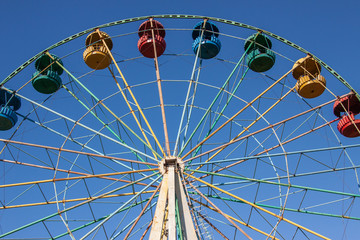 Beautiful ferris wheel. Bottom-up view. Attraction on the background of blue clear sky