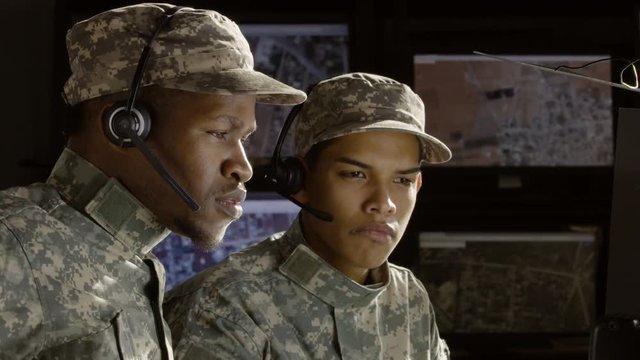 Two military drone operators consulting in front of a computer, profile shot