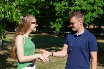 Pretty couple hugging and flirting in an urban park sitting in a bench and looking away