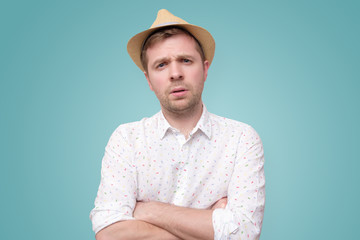 Young man in summer hat frowning showing disbelief or doubt.