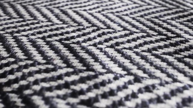 Herringbone fabric cloth close up background. Black and white tweed pattern, weaving, textile material is waving pan movement camera. 