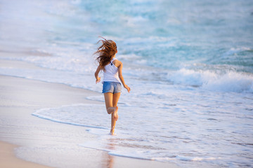 Fototapeta premium Young girl running along the beach in Dubai