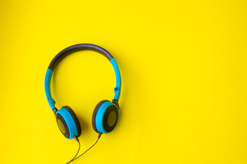 Blue headphones on yellow background.concept of entertainment