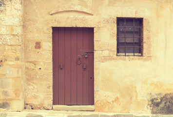 Fototapeta na wymiar The background old beige stony wall with door and a window