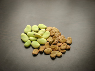 Closeup of dry and fresh broad beans seeds (Vicia faba) on wooden table