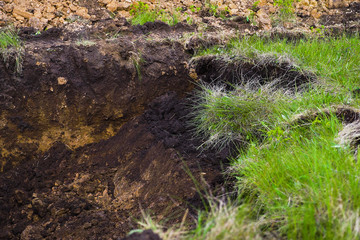 view of pit dug in brown soil with green grass on foreground