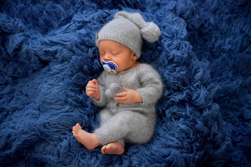 Sleeping newborn boy in the first days of life on blue background