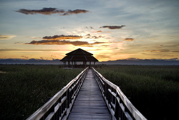 Stunning sunset behind the mountain at wooden walking bridge destination.