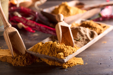 Various oriental spices with wooden spoons on a old wooden table.