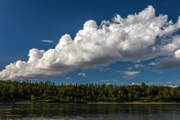 Fantastic and dreamy clouds over a forest lake