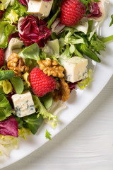 Green salad with blue cheese, raspberry and walnuts.