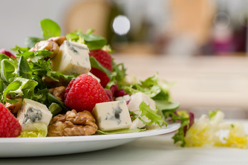 Green salad with blue cheese, raspberry and walnuts.