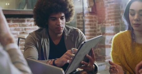 Man talking to colleagues and clients with laptop and tablet.Group of multiethnic people having informal business team meeting in restaurant lounge.Teamwork,corporate,diversity and social concepts