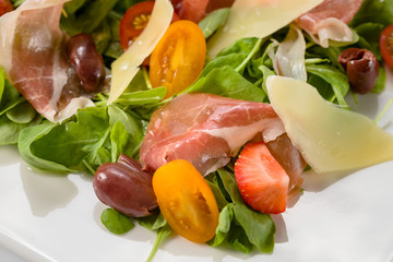 Salad with prosciutto, cheese, tomato and olives.