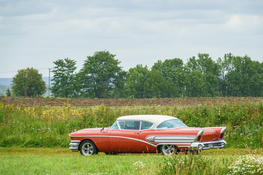 Fototapeta Old American vintage car driving in the rain at countryside