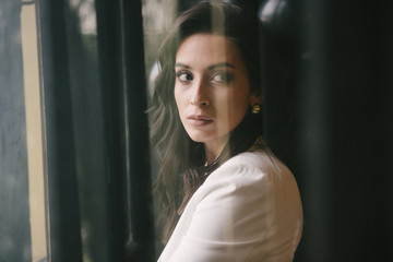 Fototapeta premium Young brunette woman posing in a suit by the window