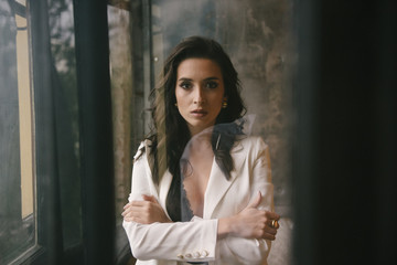Fototapeta premium Young brunette woman posing in a suit by the window