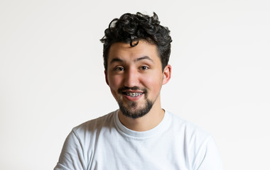 Portrait of a young man with braces smiling. A happy young man with braces on a white background