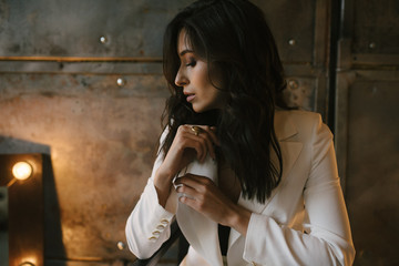 Young brunette woman posing in a suit sitting on a sofa