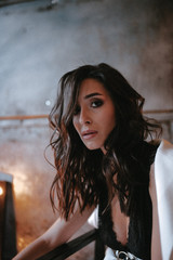 Young brunette woman posing in a suit sitting on a sofa