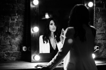 Young brunette woman looks at herself in the mirror