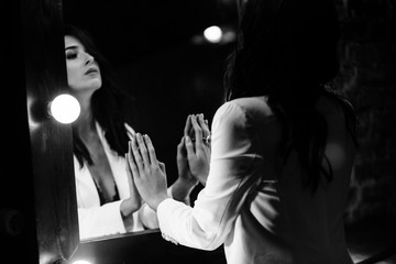 Young brunette woman looks at herself in the mirror