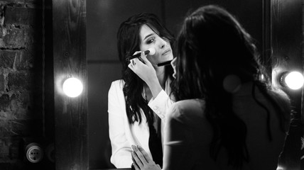 Young brunette woman looks at herself in the mirror