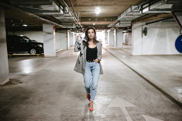 Young brunette woman posing on the underground parking lot. Woman in the parking lot.