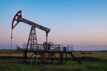 Oil and gas production equipment running at sunset