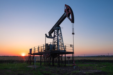Oil and gas production equipment running at sunset