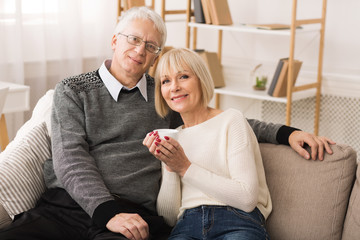 Loving Mature Couple Resting On Sofa And Looking At Camera