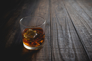glasses of whiskey with ice cubes on wooden.