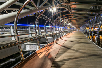 pasarela de puente para peatones de noche con estelas de luces en carretera