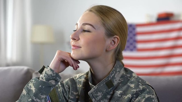 Smiling american female soldier in military uniform with US flag on background