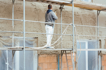 Worker plastering outer wall of newly built house