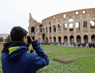 Fototapeta na wymiar young journalist with camera takes photos of Colosseum in Rome
