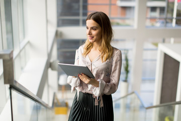 Attractive businesswoman using a digital tablet while standing on the stairs in the office