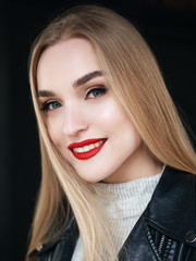 Closeup natural light beauty portrait of smiling blonde woman model with vibrant saturated red lips bright lips makeup, cheekbones and healthy shiny skin on black background.