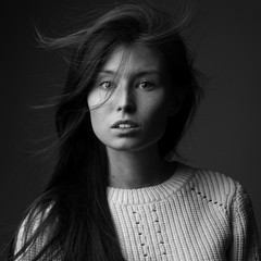 beautiful redhead model girl with long hair in the Studio on a gray background in a jacket of large knit