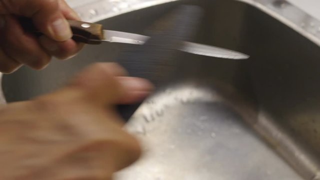 Men's Hands Sharpen The Knife With A Sharpening Stone.