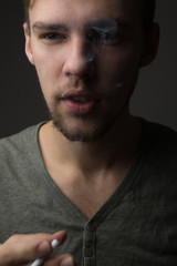 Obraz premium Portrait of a young Caucasian Smoking man with a short beard and mustache on a dark background