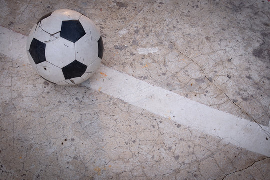 Old ruined damaged soccer ball put on cracked cement field © Koto Amatsukami