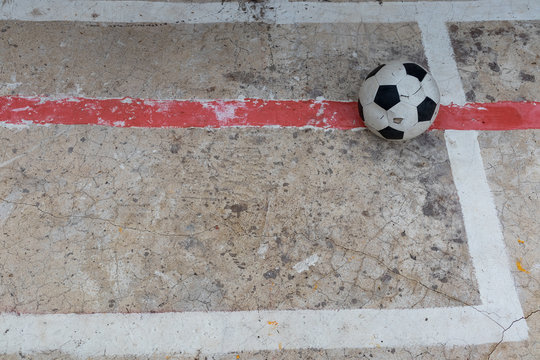 Old ruined damaged soccer ball put on cracked cement field