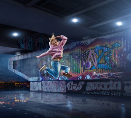 Fototapeta na wymiar Female Hip Hop Dancer. Beautiful girl dancing at night on the background of graffiti wall