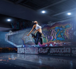 Female Hip Hop Dancer. Beautiful girl dancing at night on the background of graffiti wall