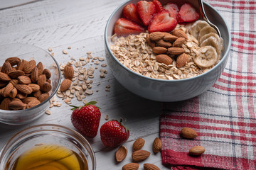 Ingredient of healthy breakfast - oatmeal with berry, honey and nuts on white background