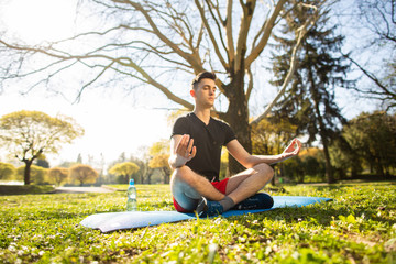 A young man relaxes and doing yoga in the green park. Concept of a healthy lifestyle